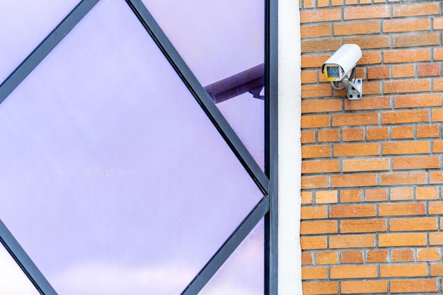 CCTV-Kameras sind an der Ziegelwand am Eingang zum Supermarkt installiert Sicherheits- und Diebstahlschutzsysteme Eine Überwachungskamera und ein gepanzertes Fenster in der Bank