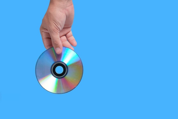 Foto cd rayado en la mano sobre un fondo azul, tecnologías obsoletas.