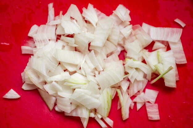 Foto cebola cortada em uma placa vermelha. preparação de ingredientes para cozinhar.