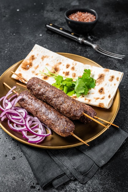 Cebola kofta kebab de carne de cordeiro e pão plano no prato Fundo preto Vista superior