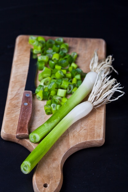 Foto cebola picada orgânica verde fresca e faca em uma placa de corte