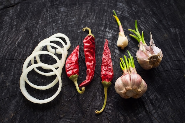 Cebola picante fatiando alho em uma mesa de madeira preta