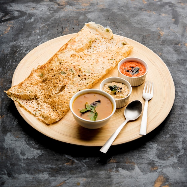 Cebola rava masala dosa é um café da manhã instantâneo do sul da Índia servido com chutney e sambar sobre um fundo melancólico. foco seletivo