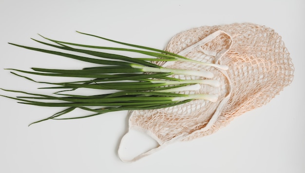 Foto cebola verde fresca em um saco ecológico na superfície branca