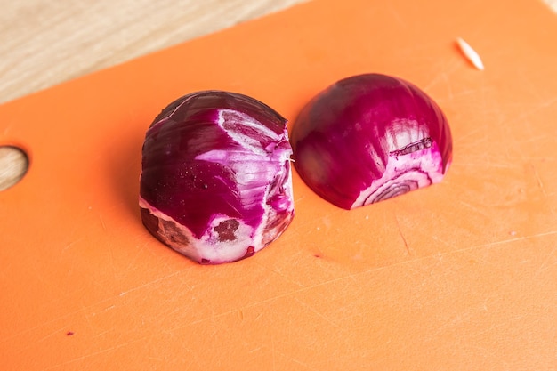 Foto cebola vermelha cortada ao meio em uma tábua