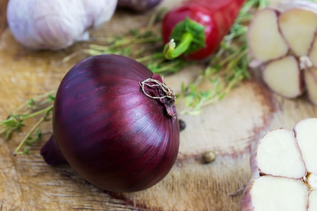 Cebola vermelha e outras especiarias em uma velha mesa de madeira