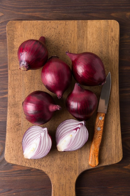 Cebola vermelha orgânica em um fundo de madeira, vegetais crus frescos.