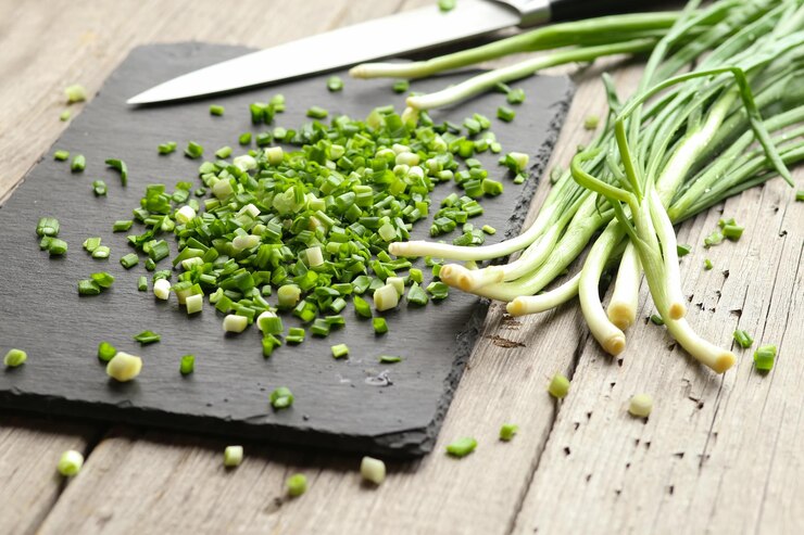 Foto cebolas verdes jovens cortadas em pedaços numa tábua preta numa mesa de madeira cozinhar alimentos alimentação saudável produtos não geneticamente modificados alimentos fortificados