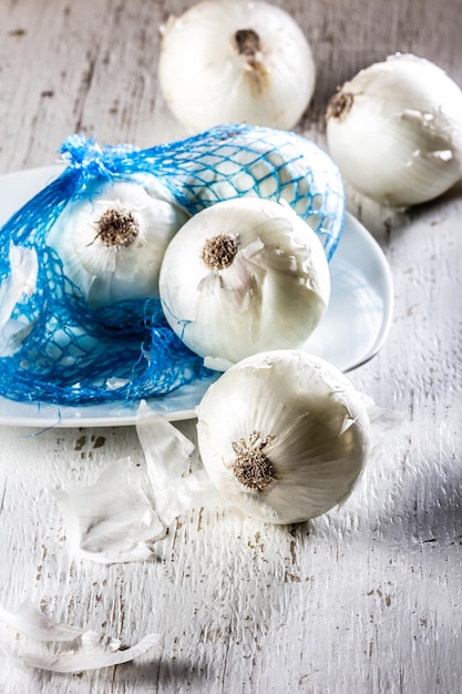 Cebolla blanca en plato blanco, fondo madera