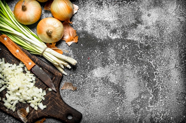 Cebolla fresca picada en el tablero antiguo sobre fondo rústico