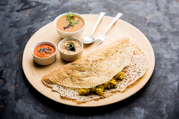 Cebolla rava masala dosa es un desayuno instantáneo del sur de la India que se sirve con salsa picante y sambar sobre un fondo de mal humor. enfoque selectivo