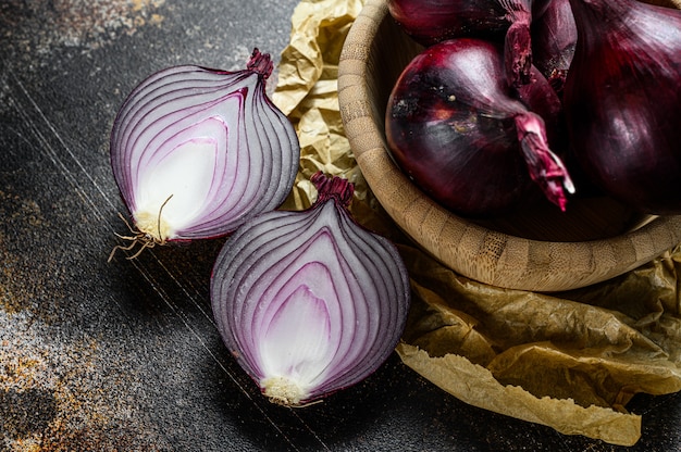 Foto cebolla roja orgánica en un tazón de madera. granja eco verduras. fondo oscuro vista superior.