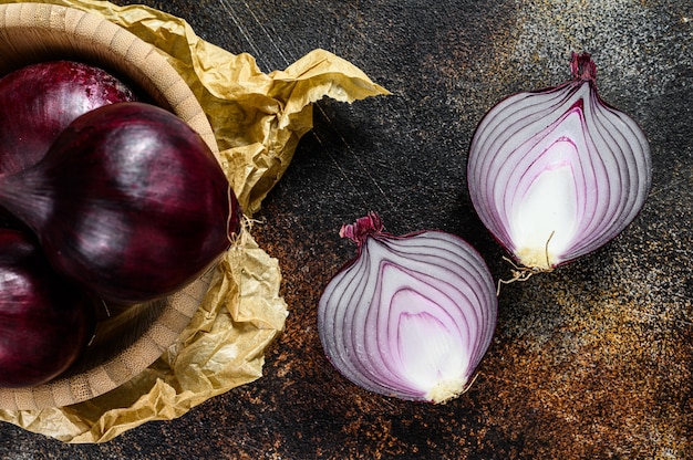 Cebolla roja orgánica en un tazón de madera. Granja eco verduras. Fondo oscuro Vista superior.