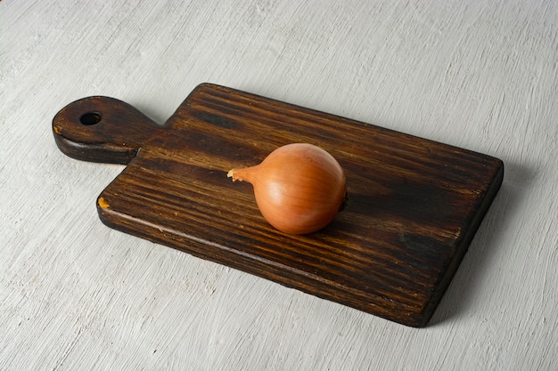 Foto una cebolla solitaria en una tabla de madera de cocina