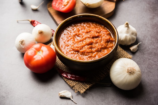 Cebolla tomate masala o puré para salsa india, servido en un bol con tamatar crudo, pays y lehsun y chile rojo,