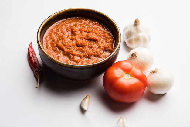 Cebolla tomate masala o puré para salsa india, servido en un bol con tamatar crudo, pays y lehsun y chile rojo,