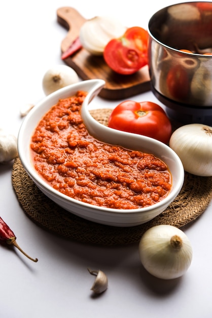 Foto cebolla tomate masala o puré para salsa india, servido en un bol con tamatar crudo, pays y lehsun y chile rojo,
