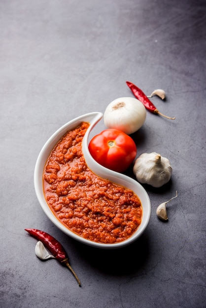 Cebolla tomate masala o puré para salsa india, servido en un bol con tamatar crudo, pays y lehsun y chile rojo,