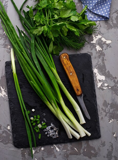 Cebolla verde fresca en tablero de pizarra