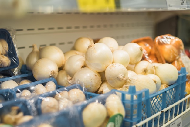 Cebollas blancas en la cesta en el estante de la tienda en el departamento de verduras del supermercado Primer enfoque selectivo
