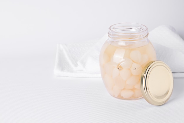 Cebollas fermentadas en un frasco sobre un fondo blanco con lugar para.