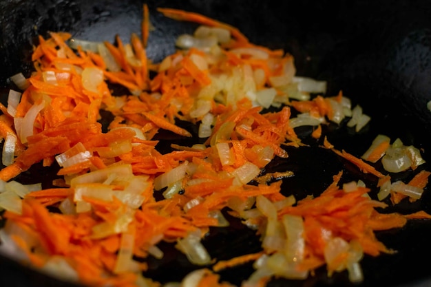 Cebollas fritas con zanahorias en una sartén closeup Preparación de ingredientes para cocinar