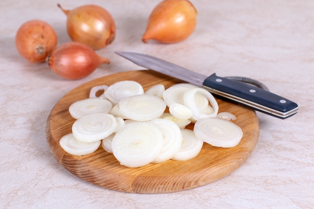 Cebollas en rodajas sobre una tabla para cortar sobre la mesa de la cocina