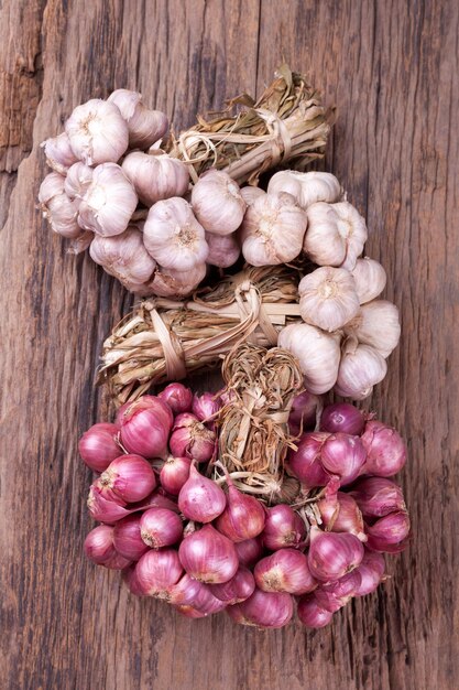 Cebollas rojas con ajo entero sobre fondo de madera