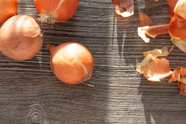 Cebollas de tinte natural y cáscaras de cebolla yacen sobre una mesa gris leñosa