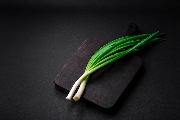 Cebollas verdes frescas en una tabla de cortar rectangular de madera