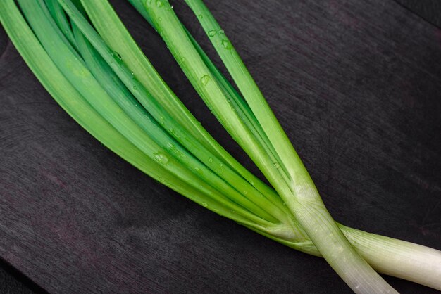 Cebollas verdes frescas en una tabla de cortar rectangular de madera