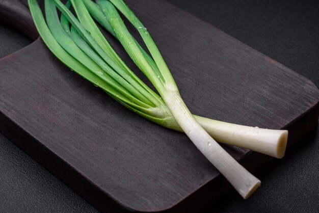 Cebollas verdes frescas en una tabla de cortar rectangular de madera