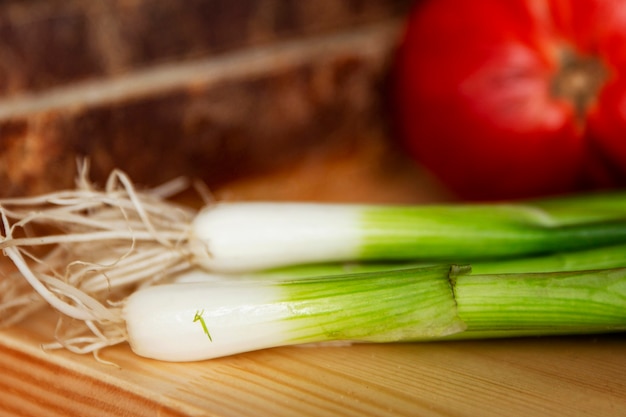 Foto cebollas verdes y verduras frescas en una mesa de madera. salud y vitaminas de la naturaleza. de cerca. enfoque selectivo.