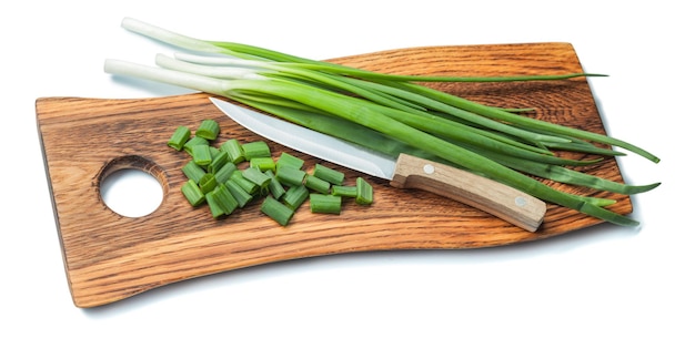 Cebolletas picadas verdes y cuchillo de cocina en una tabla de cortar de madera vintage con borde de vida aislado