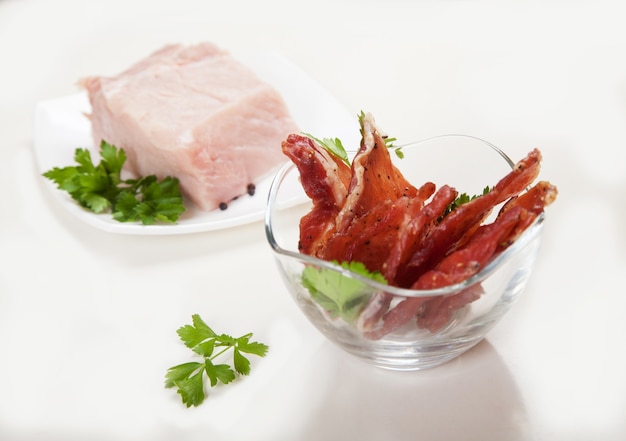 Cecina en una taza y carne cruda con hierbas en un plato blanco.