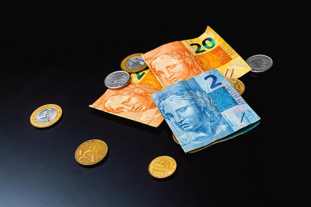 Cédulas e moedas reais do Brasil em mesa escura