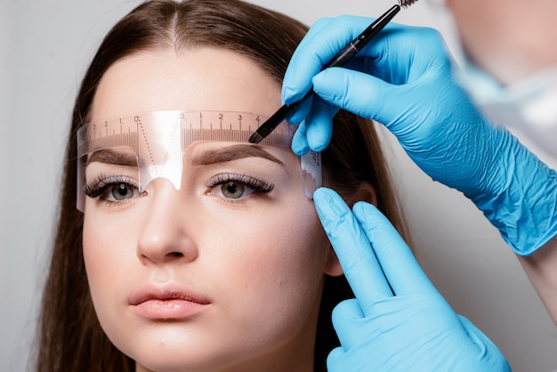 Las cejas microblading fluyen en un salón de belleza. Mujer que tiene sus cejas teñidas.