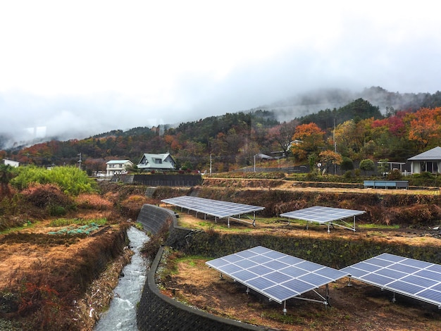 Celda solar frente a la pequeña casa rural en otoño.