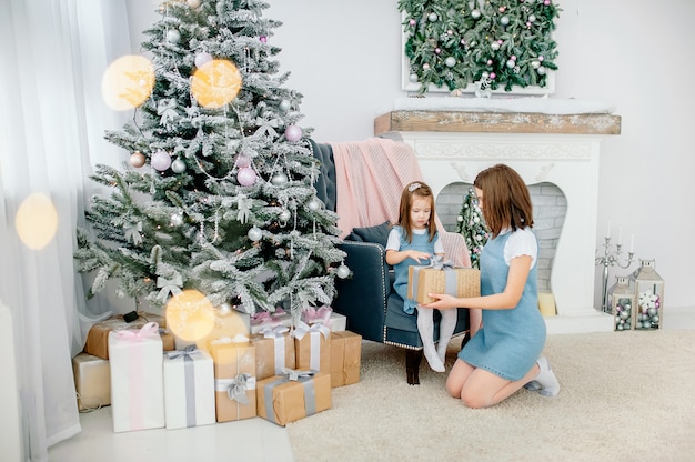 Celebra la Navidad, las emociones, los sentimientos, los momentos preciosos. madre e hija están presentando un regalo de bienvenida cerca del árbol de Año Nuevo