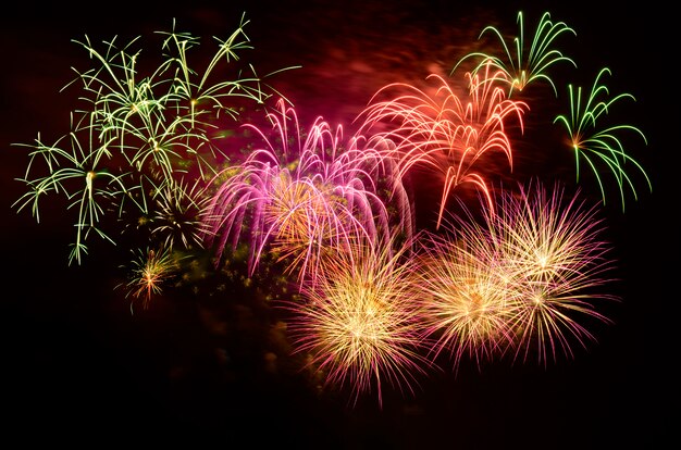 Celebração colorida dos fogos-de-artifício e o fundo do céu noturno.
