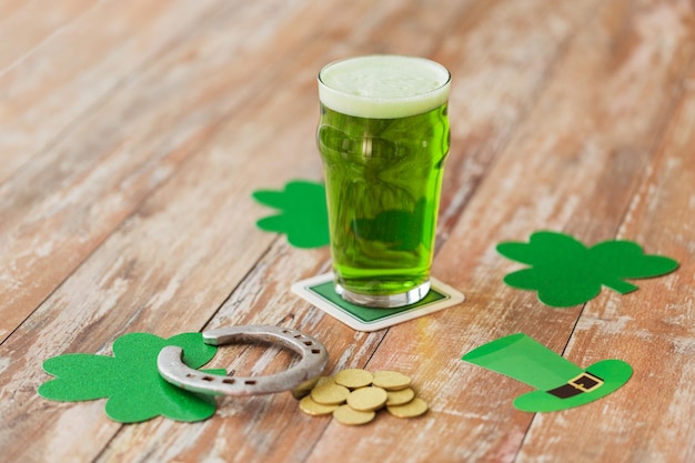 celebração de feriados e dia de São Patrício conceito copo de cerveja verde ferradura e moedas de ouro na mesa