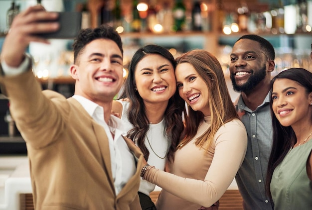 Celebração de festa e amigos tirando selfie em um telefone no bar de coquetéis para evento social de aniversário e véspera de ano novo Vida noturna de mídia social e grupo de pessoas sorriem para fotografia nas férias