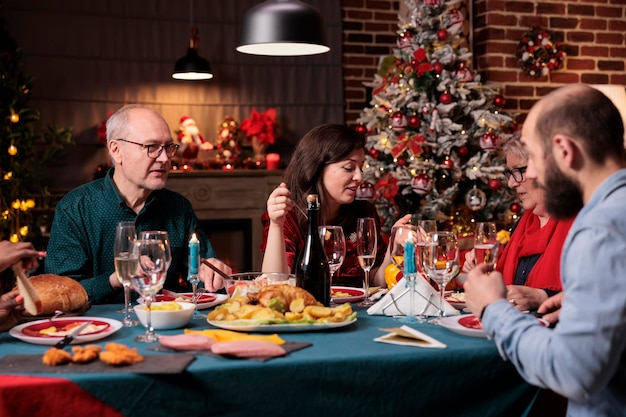 Celebração de natal em família, reunindo-se com os pais na mesa de jantar festiva na festa em casa. Pessoas conversando, comendo comida tradicional de natal, conversando, comemorando feriados