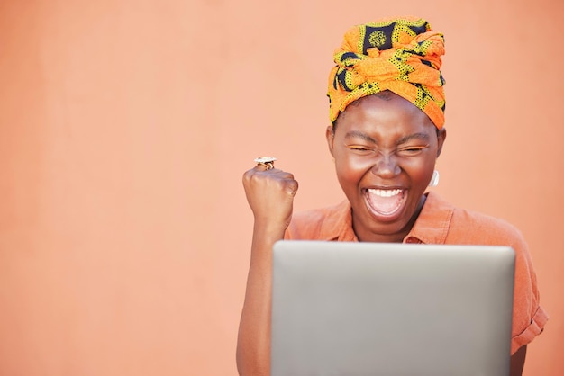 Celebração de sucesso e mulher negra no laptop depois de ganhar em um fundo de estúdio laranja simulam Vencedor de rosto e mulher no computador após ganhar na loteria online ou ler boas notícias nas mídias sociais