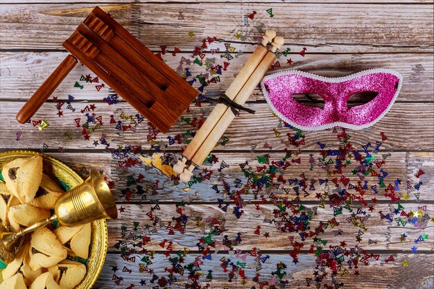 Celebração do carnaval judaico de Purim em biscoitos hamantaschen, noisemaker e máscara com pergaminho Vista superior de cima.