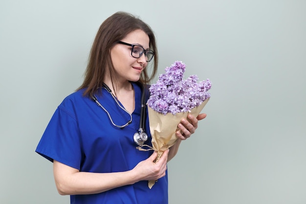 Celebração do dia do médico Feliz sorridente médica feminina com buquê de flores posando feminina olhando para a câmera fundo verde claro