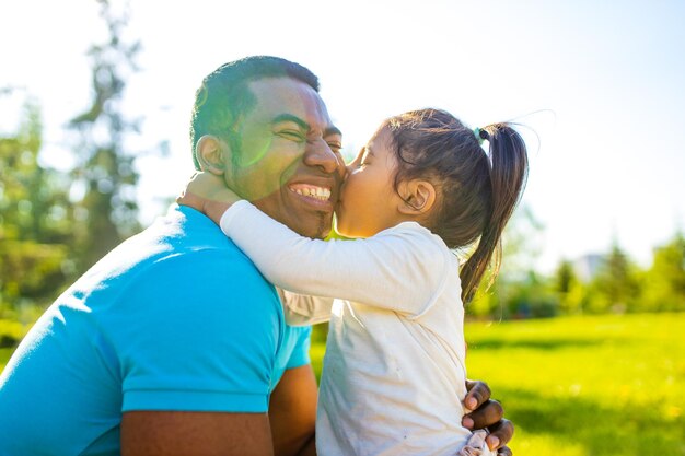 Celebração do dia dos pais feliz homem afro-americano com seu bebê fofo no parque de verão se divertindo juntos