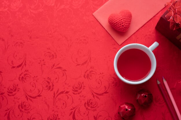 Celebração do feriado do dia de valentim com corações e copo do suco no fundo vermelho.