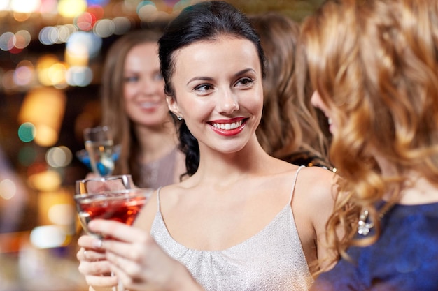 celebración, amigos, despedida de soltera y concepto de vacaciones - mujeres felices bebiendo champán y cócteles en el club nocturno
