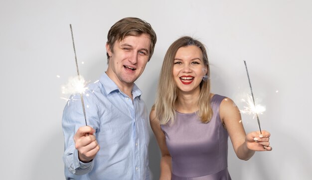 Celebración de año nuevo fiesta de navidad y concepto de vacaciones feliz hombre y mujer abrazándose sobre gris